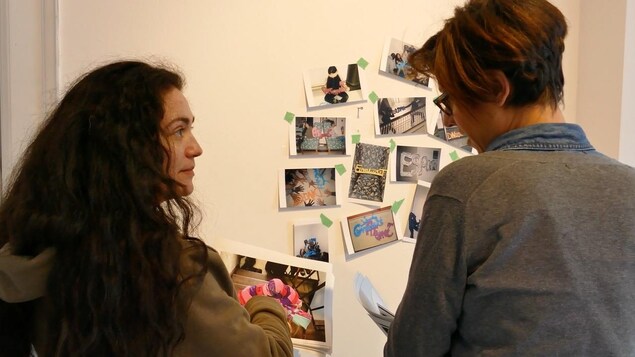 Deux femmes discutent et regardent les photos collées au mur. Deux femmes discutent et regardent les photos collées au mur.