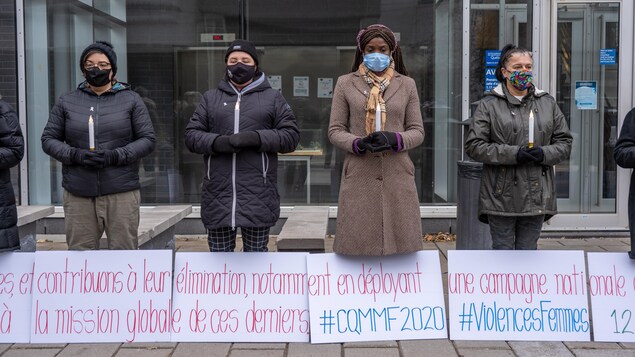 Des femmes, chandelles à la main, devant des pancartes, devant le palais de justice de Trois-Rivières.