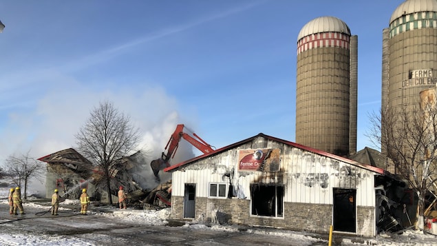 Ferme détruite avec pompiers qui arrosent encore