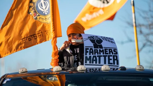 Un garçon sortant la tête d'une voiture décorée de drapeaux et d'un pancarte où l'on peut lire que les fermiers comptent.