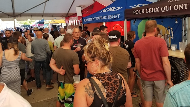 Des gens sous un chapiteau boivent de la bière.