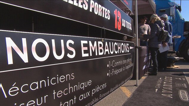 Des enseignes annonçant des postes disponibles dans l'industrie du camionnage, avec un camion en arrière-plan.