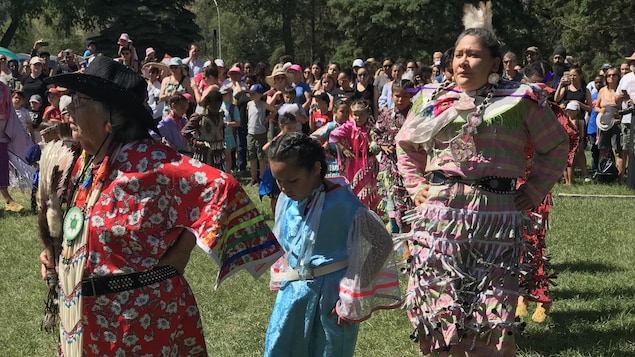 Trois femmes autochtones sont habillées en regalia traditionnel et dansent dans un Pow-wow.