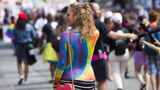 Une femme dont le dos est peint aux couleurs de l'arc-en-ciel.