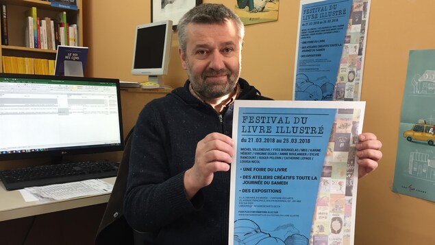 Un homme tient l'affiche du Festival du livre illustré. Un homme tient l'affiche du Festival du livre illustré.