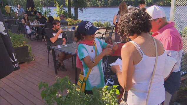 Une dame accueille des Français à la porte d'une bar.