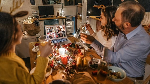 Une famille trinque en ligne avec des proches à l'occasion de Noël.