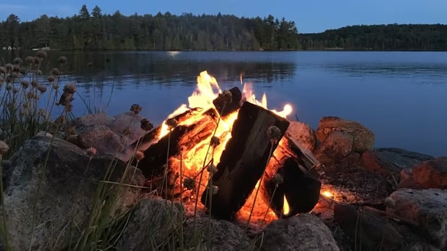 Un feu de camp brille juste après la tombée de la nuit sur le lac Joseph dans la région de Muskoka en Ontario.