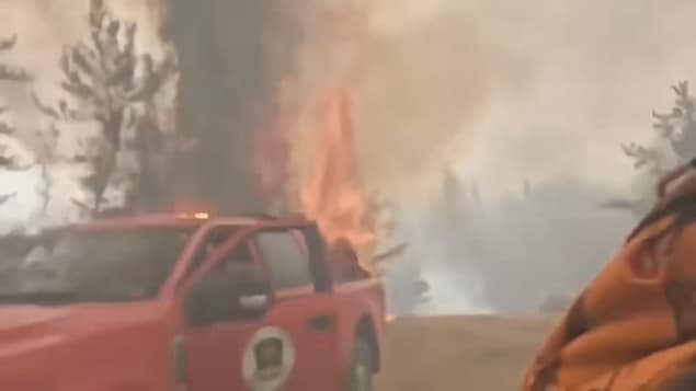 Des pompiers fuient les flammes près de Creighton, en Saskatchewan.