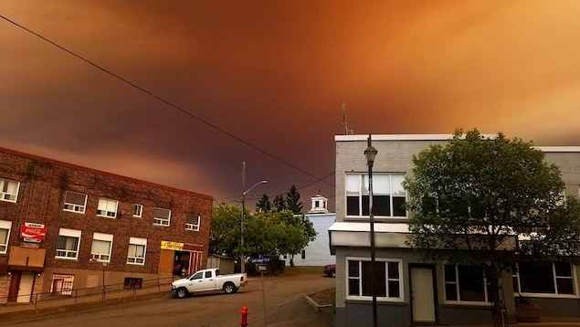 Un rue avec des commerces et le ciel d'une couleur orangée