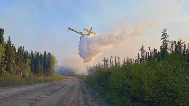 Un avion-citerne déverse de l'eau sur le feu de forêt près de Stanley Mission, en Saskatchewan, au début juin 2022.