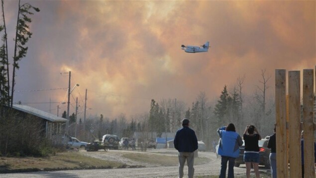 Un avion citerne survole le ciel enfumé par un feu de forêt près du secteur Stanley Mission, au nord de Lac la Ronge en Saskatchewan, le 22 mai 2014.