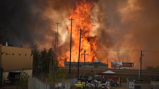 Des flammes montent jusqu'au ciel devant une maison et ce qui ressemble à une zone industrielle. Des flammes montent jusqu'au ciel devant une maison et ce qui ressemble à une zone industrielle.