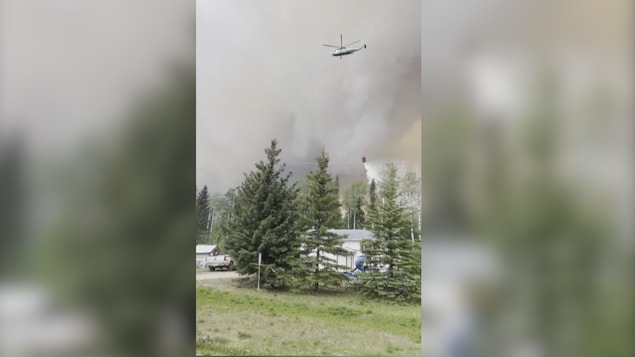 Un hélicoptère déverse de l'eau au-dessus d'un feu près de Kelly Lake, en Colombie-Britannique.