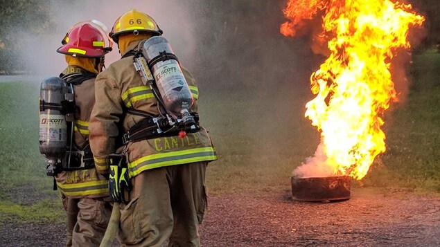Deux pompiers tentent d'éteindre un petit feu. Deux pompiers tentent d'éteindre un petit feu.