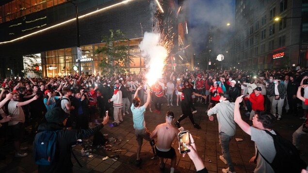 Une foule dispersée autour d'un homme qui tient des feux d'artifice.