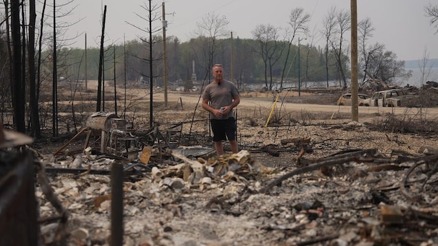 Un homme se tient debout au milieu d'un tas de ruines. 