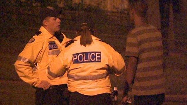 Photo de deux policiers qui interrogent un homme dans la rue.