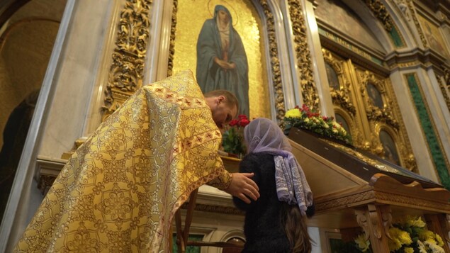 Un prêtre se penche sur une fidèle dans l'église. Un prêtre se penche sur une fidèle dans l'église.