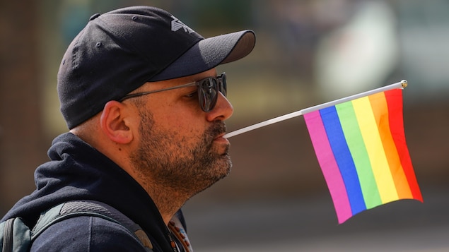 رجل يحمل راية مثليي الجنس بفمه في تظاهرة في ساسكاتون، كبرى مدن ساسكاتشِوان، في الأول من حزيران (يونيو) 2023.