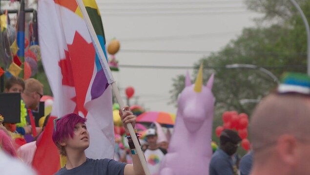 Une personne tient un drapeau mouvement LGBT et celui du Canada.