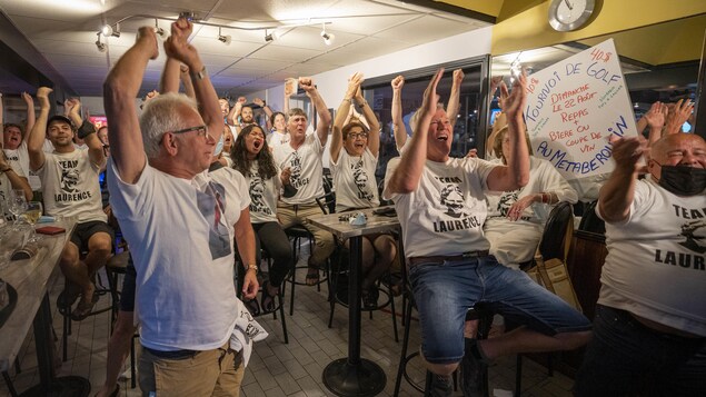 De gens les mains dans les airs, souriants, dans un bar sportif du secteur Cap-de-la-Madeleine.