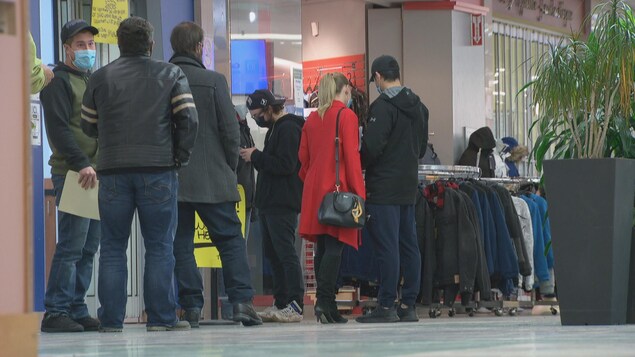 Des gens qui attendent en file avant d'entrer dans un commerce.