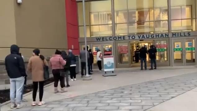 Plusieurs dizaines de clients en file près des portes du centre commercial Vaughan Mills.