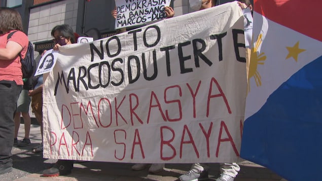Mga nagpoprotesta may hawak na banner na nagsasabing 'No to Marcos Duterte, demokrasya para sa bayan.'