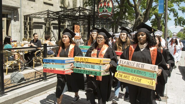 Plusieurs jeunes femmes tiennent des affiches et marchent sur le trottoir.