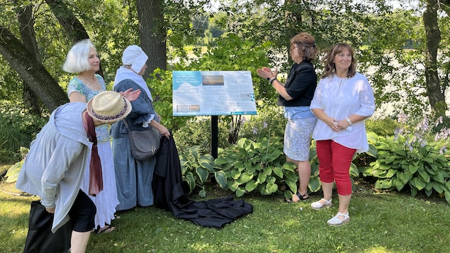 Des femmes qui inaugurent le panneau d'interprétation.