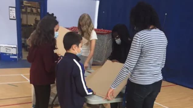 Des élèves travaillent dans un gymnase autour d'une table.