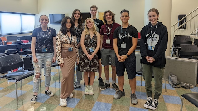 Huit jeunes sourient à la caméra.