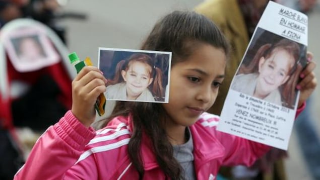 Une fillette tient dans ses mains des affiches montrant le visage de la petite Fiona lors d'une marche tenue en sa mémoire le 6 octobre 2013, à Paris, en France. Une fillette tient dans ses mains des affiches montrant le visage de la petite Fiona lors d'une marche tenue en sa mémoire le 6 octobre 2013, à Paris, en France.
