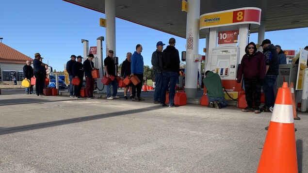 Des dizaines de personnes font la file pour acheter de l’essence.