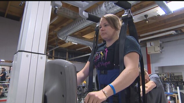 Une femme avec un handicap s'entraîne sur un tapis roulant.