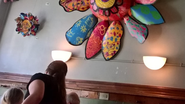 La « fleur officielle d'Athens » accrochée au mur du restaurant Casa Nueva pendant qu'une serveuse apporte les plats de deux clients. La « fleur officielle d'Athens » accrochée au mur du restaurant Casa Nueva pendant qu'une serveuse apporte les plats de deux clients.