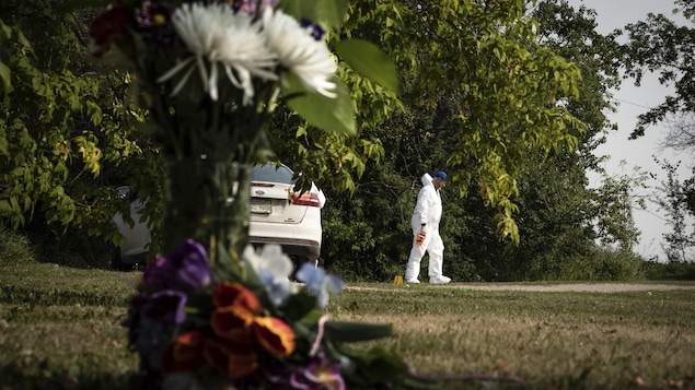 A crime scene investigator in Weldon, Saskatchewan, with a bouquet of flowers in memory of a victim of the September 4, 2022 knife attacks.