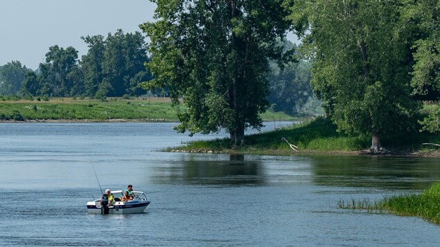 Trois hommes pêchent à bord d'un bateau à moteur sur le fleuve St-Laurent. Trois hommes pêchent à bord d'un bateau à moteur sur le fleuve St-Laurent.
