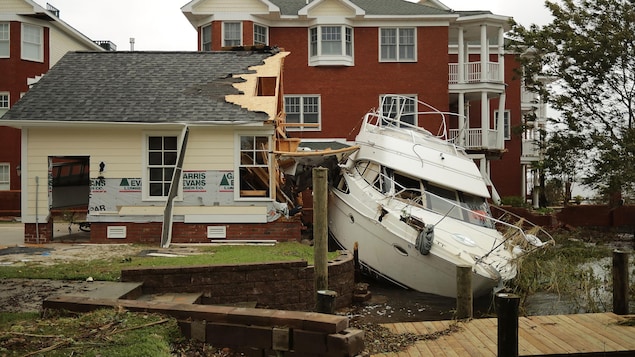 Un bateau blanc est à côté d'un garage en rénovation dont l'un des murs a été défoncé par le véhicule. Un bateau blanc est à côté d'un garage en rénovation dont l'un des murs a été défoncé par le véhicule.