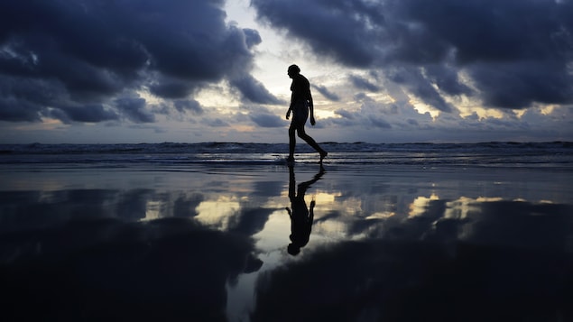 Un homme marche sur une plage de Daytona Beach vendredi matin.