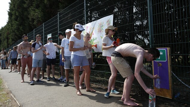 Des spectateurs du tournoi de Winbeldon remplissent leurs bouteilles d'eau. Des spectateurs du tournoi de Winbeldon remplissent leurs bouteilles d'eau.