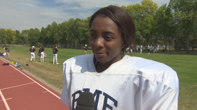 Kayara Donaldson en habits de football sur un terrain de sport parle en entrevue. Kayara Donaldson en habits de football sur un terrain de sport parle en entrevue.