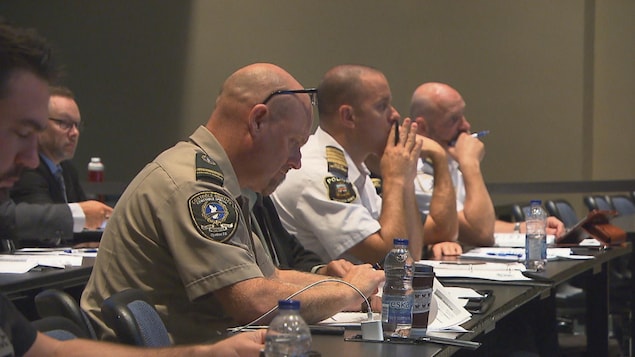 Des policiers assis à une table, qui assistent à une formation. Des policiers assis à une table, qui assistent à une formation.