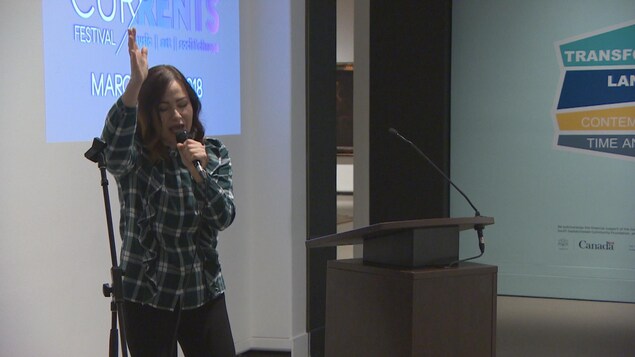 Eekwol chante au micro, le bras levé avec conviction Eekwol chante au micro, le bras levé avec conviction