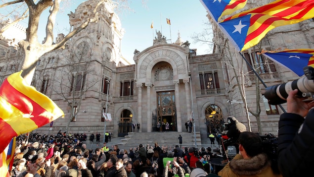 Des centaines de personnes brandissent des drapeaux de la Calalogne devant le palais de justice.
