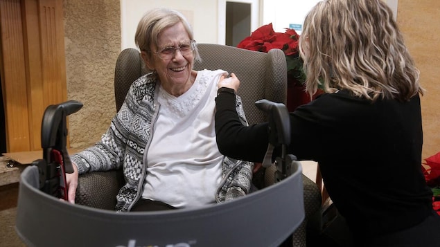 Margaret Watson sourit en recevant un vaccin dans le bras gauche.