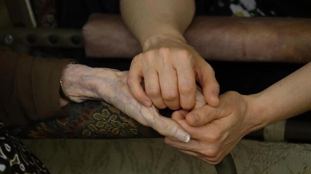 Une femme tient les mains d'une aînée.