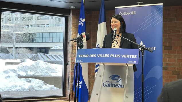 France Bélisle, derrière un podium, pendant une conférence de presse. 