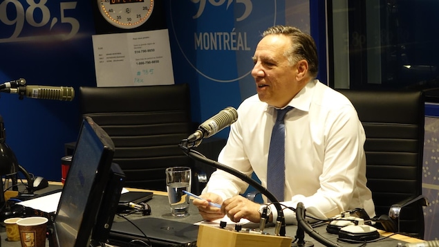 François Legault, dans un studio de radio, parle dans un micro.